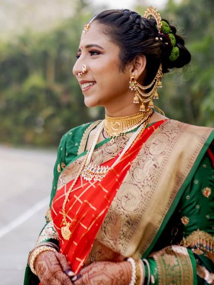 A classic portrait of a beautiful Marathi bride. Her look features a traditional nauvari saree, a choker necklace, and a braided bun with fresh flowers, creating a perfect blend of tradition and elegance.