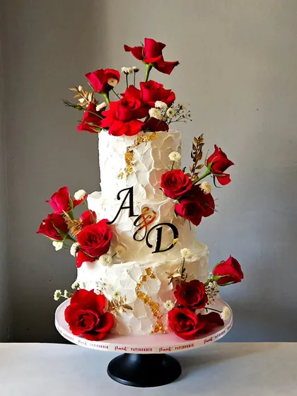 For an engagement that speaks of passion and elegance, I designed this three-tiered whipped cream cake. The contrast of the textured ivory frosting with the deep red of fresh roses and touches of gold leaf creates a timeless and romantic statement.