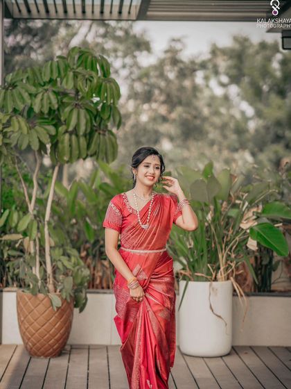 A full-length shot of a bride in her red engagement saree, looking happy and radiant.