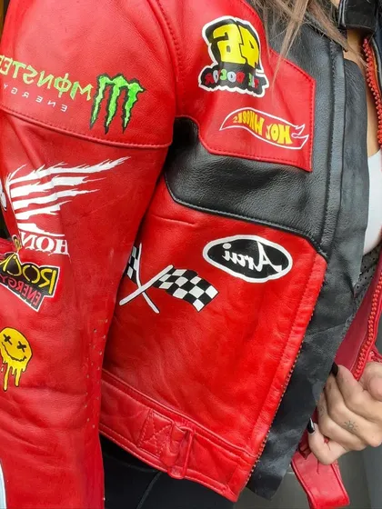 Another angle of the biker jacket, showing off the different patch designs like the smiley face and checkered flags.