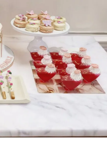 Another view of the ballerina dessert table, highlighting the variety of treats offered. You can see the butterfly-topped macarons, heart-shaped jelly cups, and floral chocolate sticks, all designed to complement the main cake and theme.