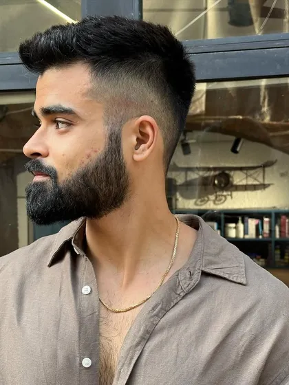 A great example of a modern men's haircut. This style features a sharp high-fade on the sides that cleanly transitions into a textured, voluminous top, paired with a perfectly groomed beard for a polished and contemporary look.