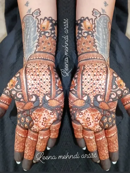This is a unique bridal design featuring large peacock feathers extending up the back of the hands. The palms are filled with intricate patterns, creating a dramatic and beautiful effect.