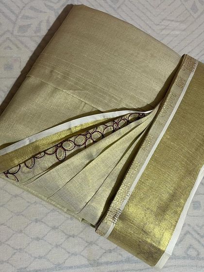 A lovely Kerala kasavu saree with a delicate embroidered border. I take special care with such fabrics to ensure the pleats are neat without damaging the material.