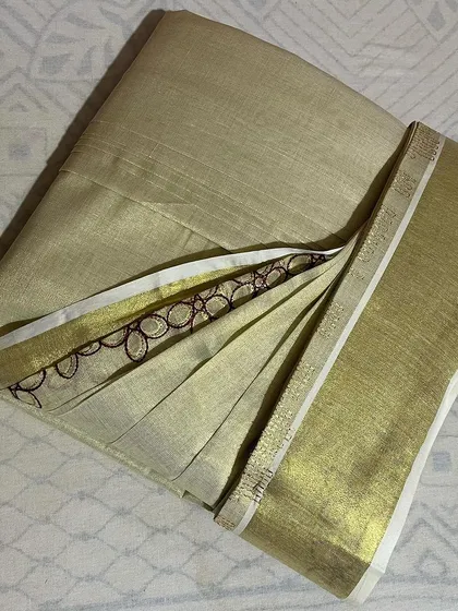 A classic Kerala Kasavu saree, folded carefully to protect its delicate fabric and gold border.