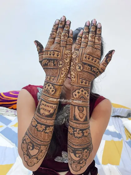 This back-hand bridal design includes personalized initials and a small portrait, hidden among the traditional patterns. It's a beautiful way to add a secret, meaningful touch to your mehendi.