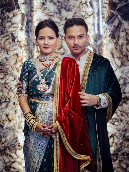 A formal portrait of the royal couple against a marble backdrop. Their coordinated green and red outfits, combined with their confident poses, create an image of pure elegance.
