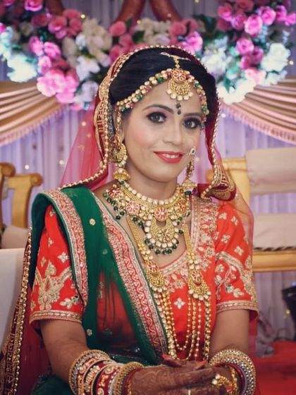 Seated in her bridal glory, this client showcases a full traditional jewellery set that perfectly matches her green and orange saree.