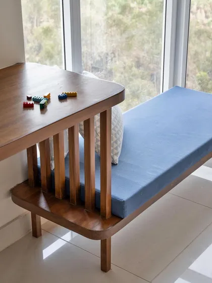 A detail shot of the custom-designed study desk that flows into a window lounge bench. The curved edges and vertical wooden slats add a touch of playful craftsmanship to this functional piece.