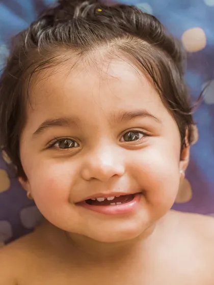 A heart-melting close-up of a smiling baby. This portrait captures the pure, unfiltered happiness of a child, with their bright eyes and joyful grin.