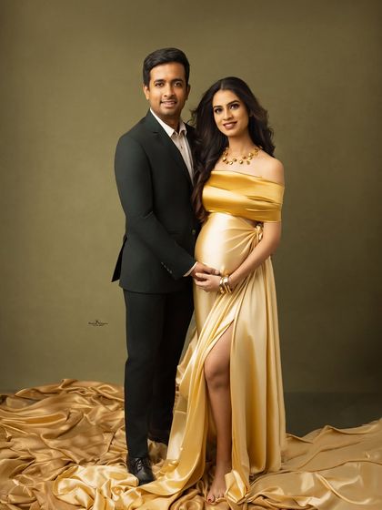 A classic and elegant couple's portrait. They stand together, radiating happiness and anticipation, dressed in glamorous attire for their maternity shoot.