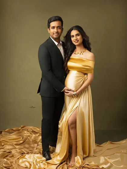 A full-length portrait showcasing a stunning golden maternity gown. The couple stands together, exuding confidence and glamour in this modern and stylish shot.