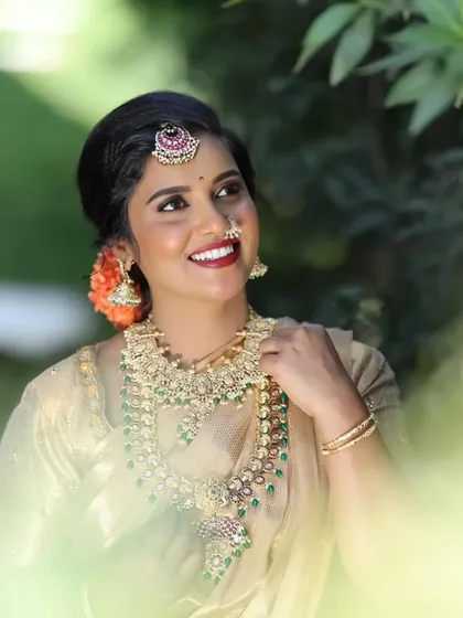 An outdoor shot capturing the natural beauty of the bride and the intricate details of the Kempu jewellery.