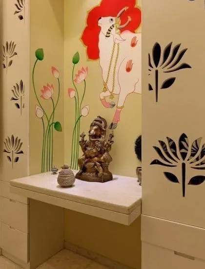 This custom pooja space combines modern cabinetry with traditional Indian art. The side panels of the unit feature delicate lotus jali cutouts, while the back wall is adorned with a hand-painted Pichwai-style mural of a cow and lotus flowers. It’s a wonderful way to create a unique and personal mandir within a niche in your home.