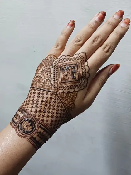The back of the hands deserves just as much love. Here is an intricate design featuring a mix of geometric grids, delicate netting, and a lotus motif cuff, perfect for a modern bride.