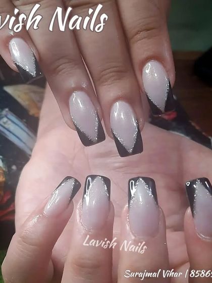 A modern and graphic V-shaped French manicure in black with a silver glitter outline.