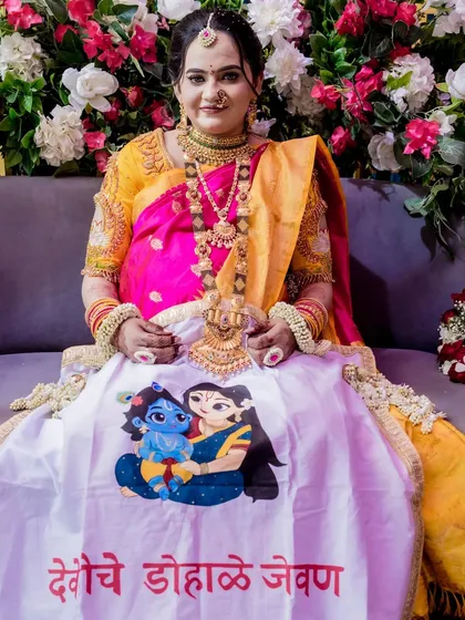 A beautiful mom-to-be at her *dohale jevan*, wearing a custom 'oti rumal' that reads "देवश्रीचे डोहाळे जेवण". We provided the doll setup to complete her celebration.