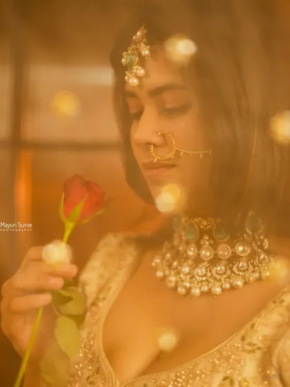 A dreamy and romantic bridal portrait. Using a soft focus and warm, glowing lights, this shot captures the bride in a quiet moment with a rose, creating a magical and ethereal feel.