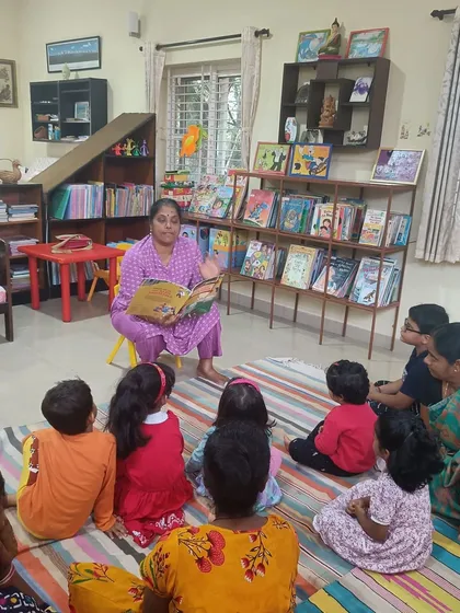 Children listen to a story about friendship and kindness. The low, accessible bookshelves in the background show how our space is designed for little readers.