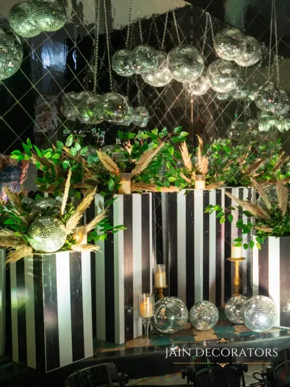 Glam meets greenery in this unique bar setup. I contrasted bold black-and-white stripes with lush botanicals and a cascade of shimmering disco balls for a chic and stylish cocktail corner.