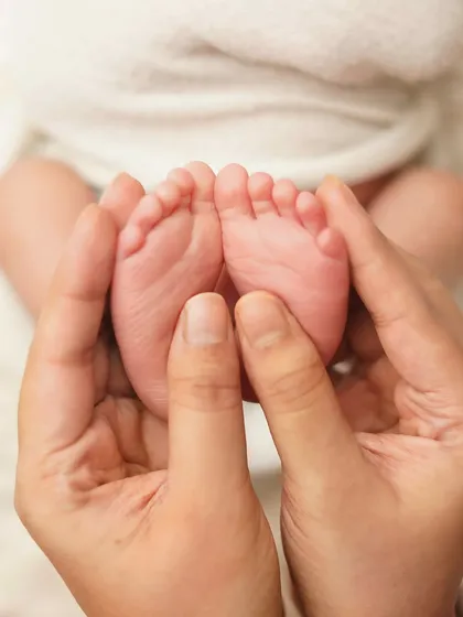 A parent's hands gently cup their newborn's feet. These detail shots are a must-have in any newborn gallery, a reminder of their tiny beginnings.