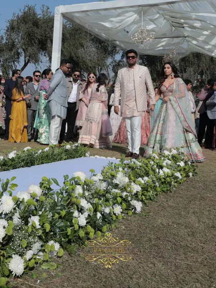 The couple makes their grand entrance, walking down an aisle lined with white flowers.