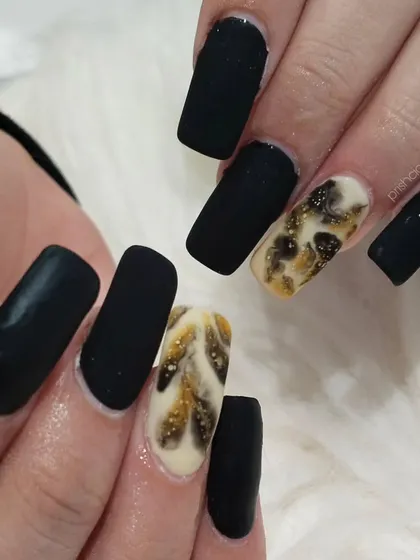 A chic and edgy set featuring a matte black finish with a smoky, marble-like accent nail in black and gold.