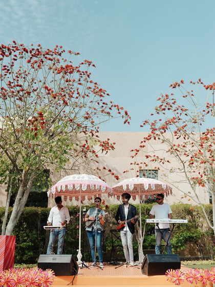 The live band performing under beautiful printed parasols, perfectly integrated into the garden Mehendi decor. The stage was set against a backdrop of blooming trees for a natural, organic feel.