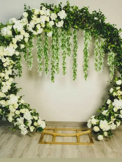 This elegant floral ring combines a full circle of greenery and white roses with delicate hanging wisteria for a romantic, garden-like feel.