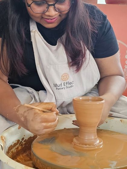 A student carefully trimming her piece on the wheel. This is an important step in refining the shape and giving it a finished look.