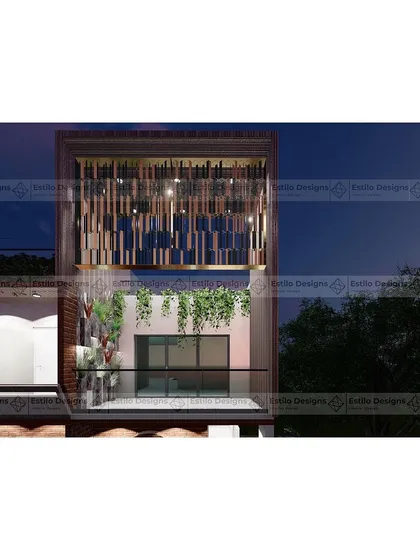 A close-up detail of the Twin House facade at night. This view highlights the intricate metal screen on the upper level, which provides privacy while creating a beautiful light pattern, adding a decorative element to the contemporary design.