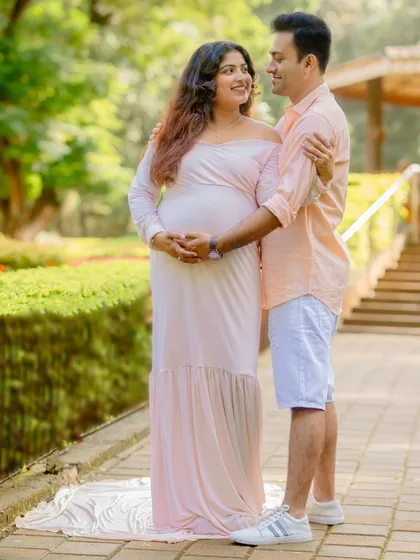 A full-length portrait of the couple, showcasing the beautiful flow of the maternity gown and their happy connection.