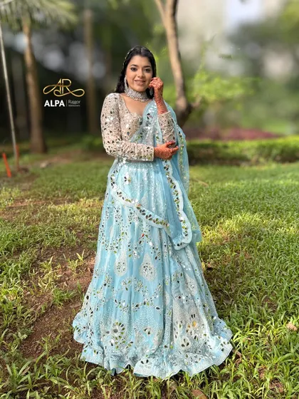 A perfect Sangeet look featuring a stunning mirror-work lehenga. The makeup is kept fresh and glowing, with a soft glam eye and a unique braided hairstyle to complement the entire outfit.