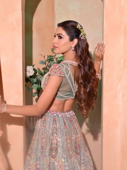 A side-back view showing the details of the half-updo with floral accessories and the beautiful cascade of waves.