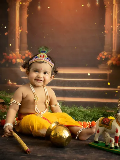 A happy, seated portrait of the baby in his festive Janmashtami setup.