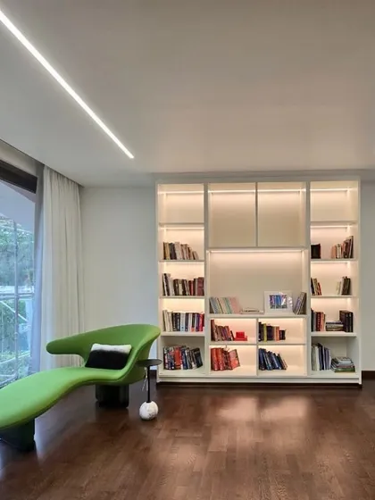 I love creating cozy corners for quiet moments. This reading nook is a perfect example of modern minimalist design, with a vibrant green chaise lounge for a pop of color and a custom, back-lit bookshelf that is both beautiful and functional.