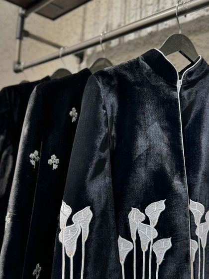 A close-up of a black velvet jacket with beautiful white lily embroidery, a stunning example of wearable art.