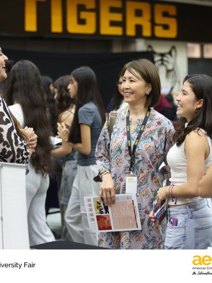 Students and faculty share a smile while exploring university brochures. Our counselors and teachers are actively involved in the fair, helping guide students and foster a relaxed, encouraging atmosphere for exploration.