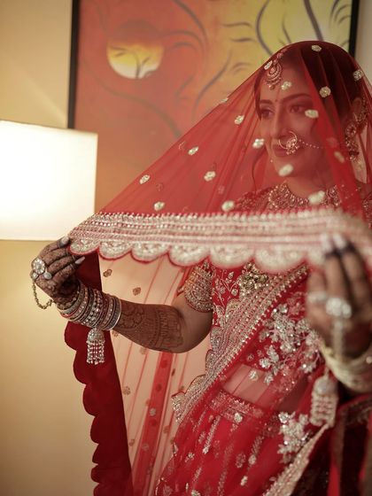 The bridal veil or ghunghat shot is iconic. The makeup is applied to look soft and radiant even when partially covered, creating a sense of mystery and elegance.