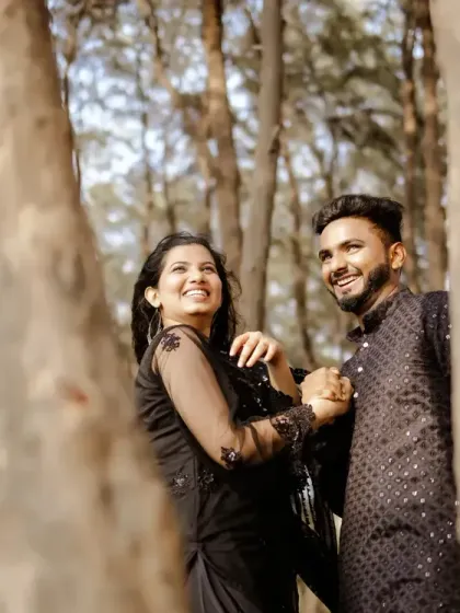 A candid, happy moment between the couple, framed by trees during their beach pre-wedding shoot. Their laughter is infectious.