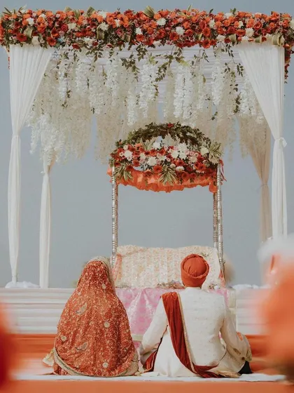 The couple sits before the Guru Granth Sahib during their Anand Karaj, a powerful and symbolic image of the ceremony.