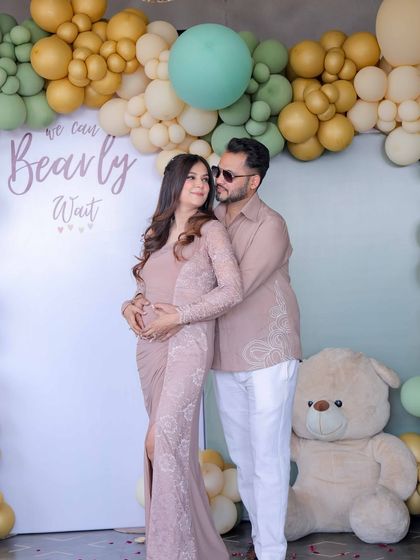 The happy couple posing at their photo booth. The 'We Can Bearly Wait' backdrop and soft balloon colors create a romantic and celebratory setting.