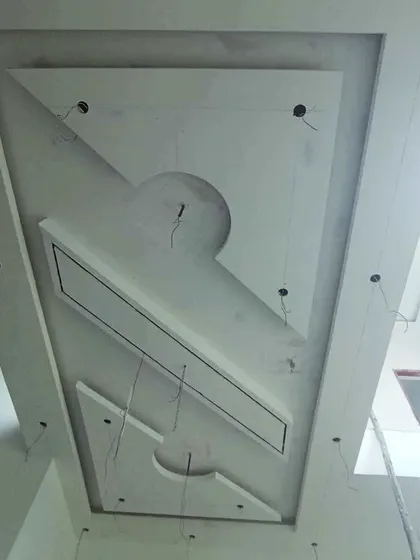 A modern, asymmetrical gypsum ceiling design with rectangular and semi-circular elements, shown with wiring ready for lights.