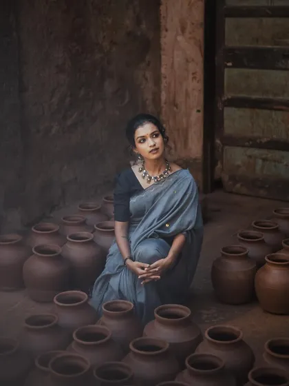A unique composition featuring the model surrounded by earthen pots. Her thoughtful expression and the rustic setting create a story-driven portrait that is both artistic and grounded.
