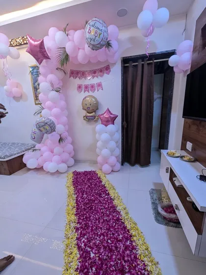 Another beautiful welcome home setup for a baby girl. This decoration includes a pink and white balloon arch, a balloon pillar, and a stunning floor runner made entirely of deep pink flower petals.