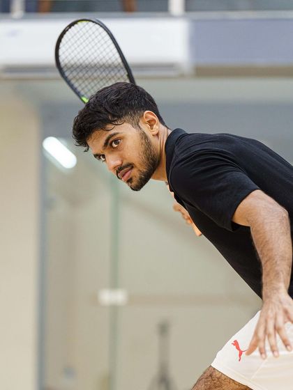 A dynamic action portrait of Rahil Peris preparing to hit a backhand. The angle highlights his form and readiness, capturing the explosive potential just before impact.