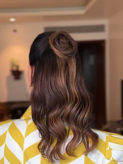 A chic and modern half-updo with a top knot, perfect for a stylish event or a party. The waves add softness to the look.
