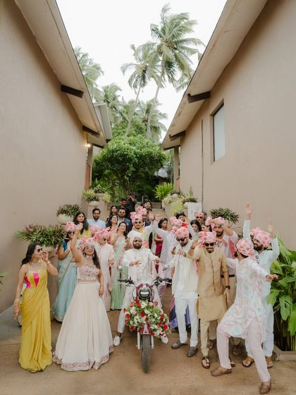 The groom and his entire Baraat crew pose for a high-energy group photo, with the groom on his decorated Bullet.