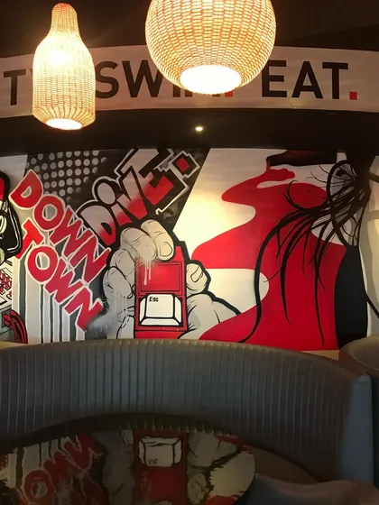 This part of the Downtown Dive mural uses strong graphic elements and a limited color palette of red, black, and white to create a cohesive and stylish look.