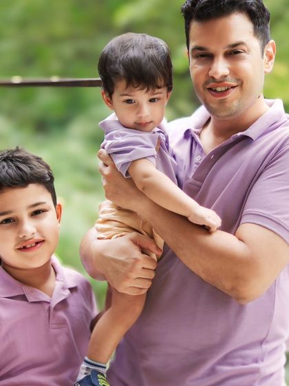 A beautiful portrait of a father and his two sons, showcasing their bond. The soft outdoor light creates a warm and timeless feel.
